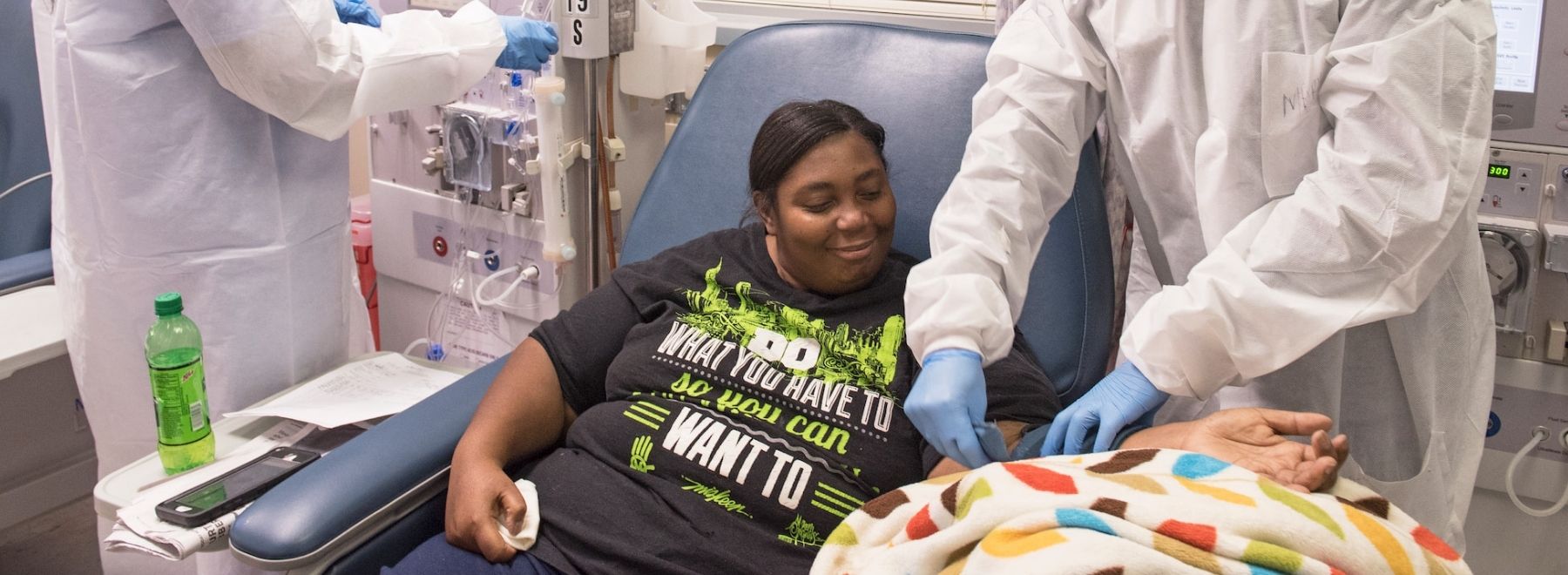 A patient smiles as a clinician prepares her for kidney dialysis.